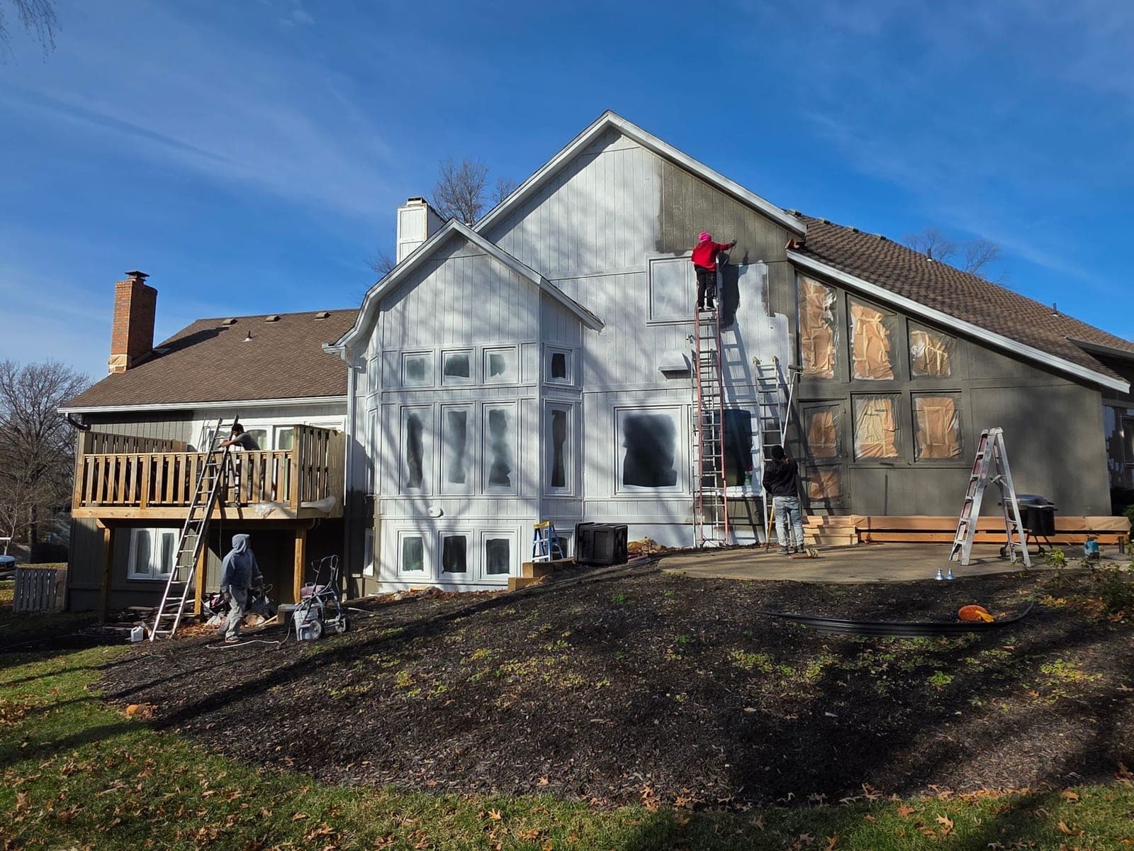 Mission Painting crew members on ladders painting the exterior of a Kansas City home